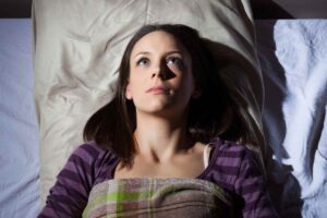 giovane donna a letto con occhi aperti