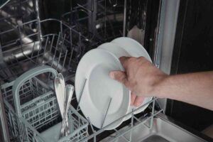 mano che prende un piatto dalla lavastoviglie