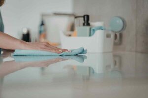 mano che pulisce le superfici del bagno